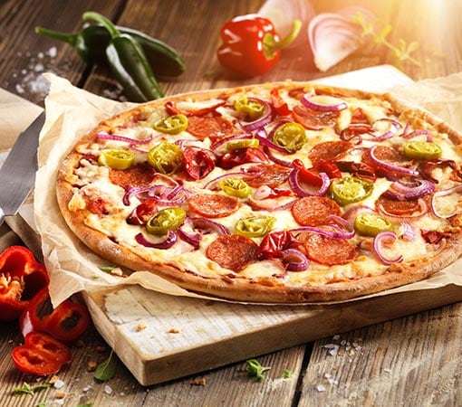 Image: Pizza au salami, pepperoni et oignons sur une planche de bois